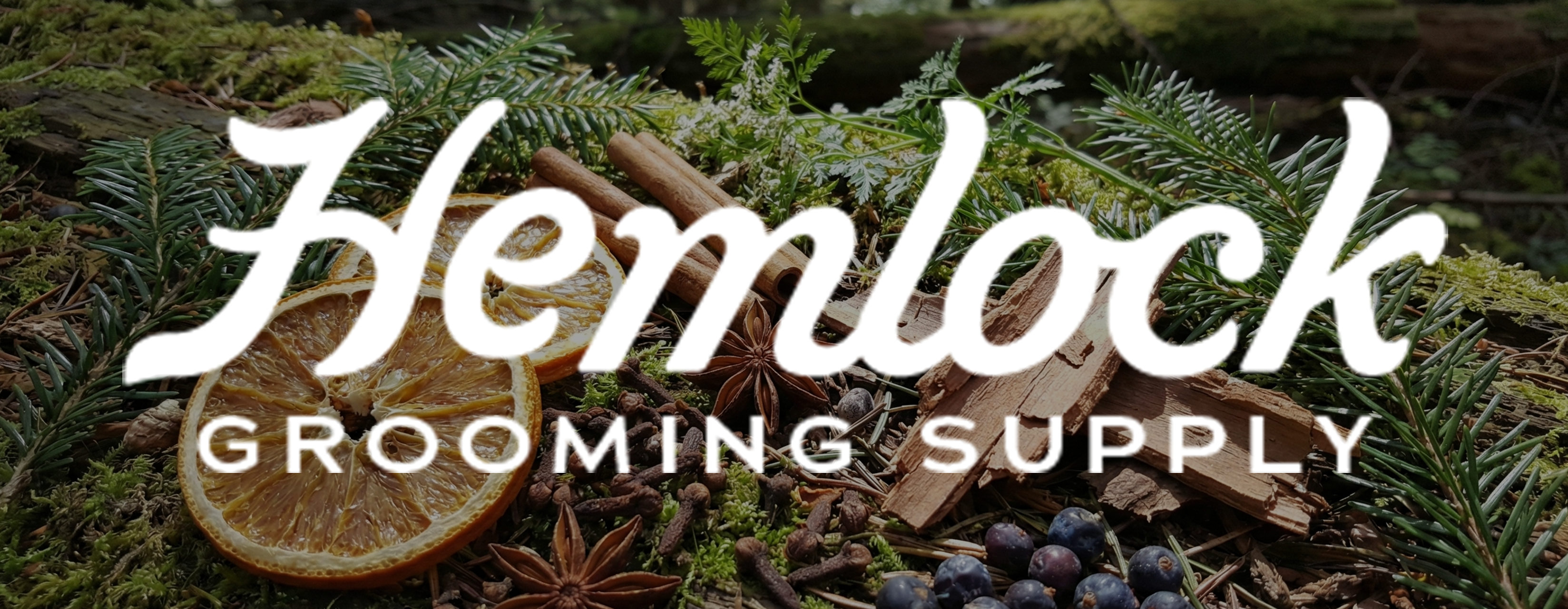 Hemlock Grooming Supply logo over natural fragrance ingredients including citrus slices evergreen branches spices and wood highlighting the brands signature woody citrus spice scent inspired by the outdoors.